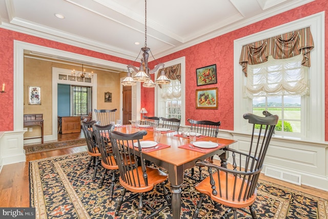 dining room featuring wallpapered walls, visible vents, wainscoting, wood finished floors, and a healthy amount of sunlight