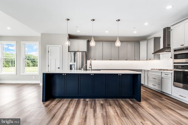 kitchen featuring wall chimney exhaust hood, appliances with stainless steel finishes, light countertops, and gray cabinetry