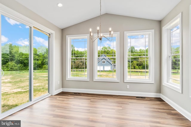 unfurnished dining area with baseboards, vaulted ceiling, wood finished floors, and a chandelier