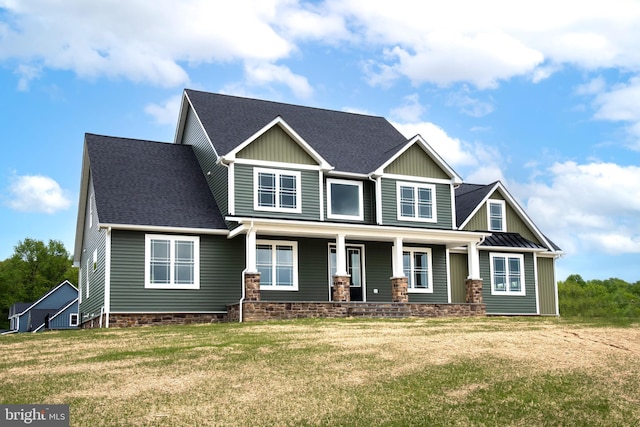 craftsman house with a porch, roof with shingles, and a front yard