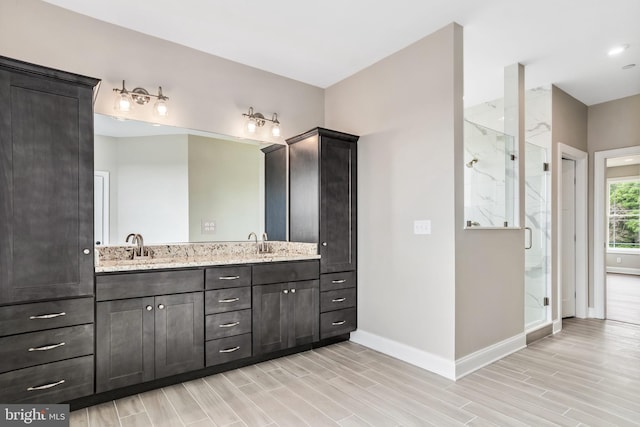 full bathroom with wood tiled floor, baseboards, a sink, and a marble finish shower