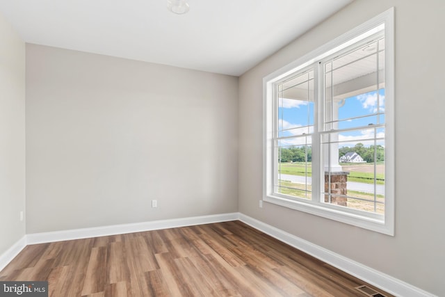 unfurnished room with visible vents, baseboards, and wood finished floors