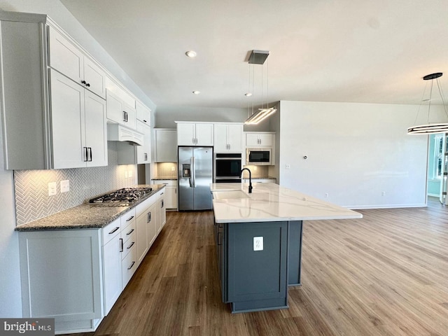 kitchen with stainless steel appliances, white cabinetry, a center island with sink, and pendant lighting