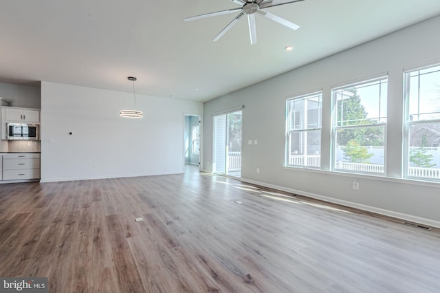 unfurnished living room with light wood finished floors, plenty of natural light, and baseboards