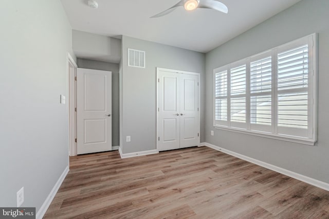 unfurnished bedroom featuring light wood finished floors, baseboards, visible vents, a ceiling fan, and a closet