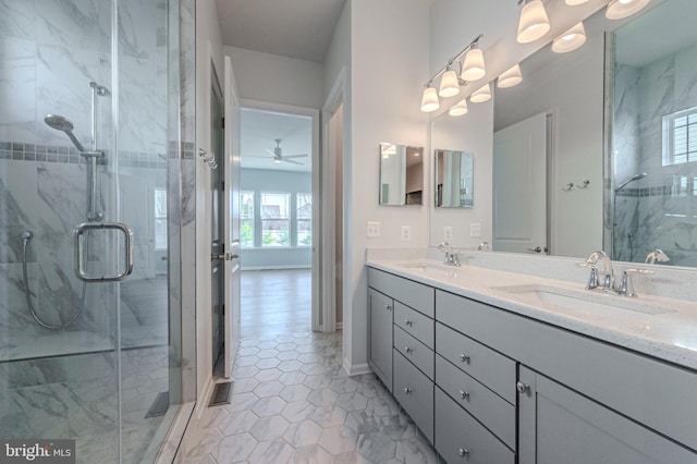 full bathroom with double vanity, ceiling fan, a marble finish shower, and a sink