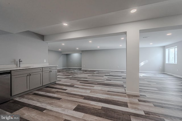 basement with light wood finished floors, recessed lighting, a sink, and baseboards