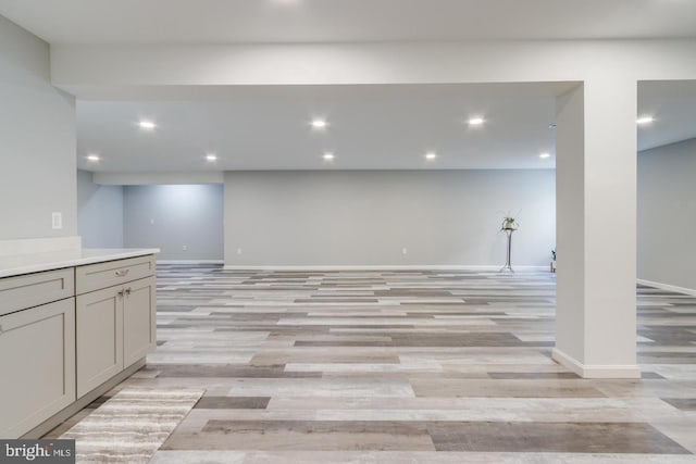 finished basement featuring light wood-type flooring, baseboards, and recessed lighting