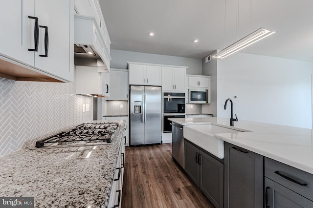 kitchen featuring a sink, white cabinetry, hanging light fixtures, appliances with stainless steel finishes, and light stone countertops