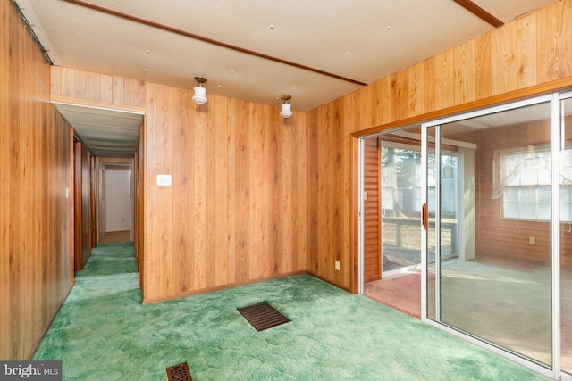 carpeted empty room with visible vents and wooden walls