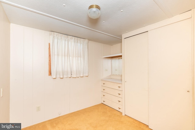 unfurnished bedroom featuring a closet, light colored carpet, and a textured ceiling