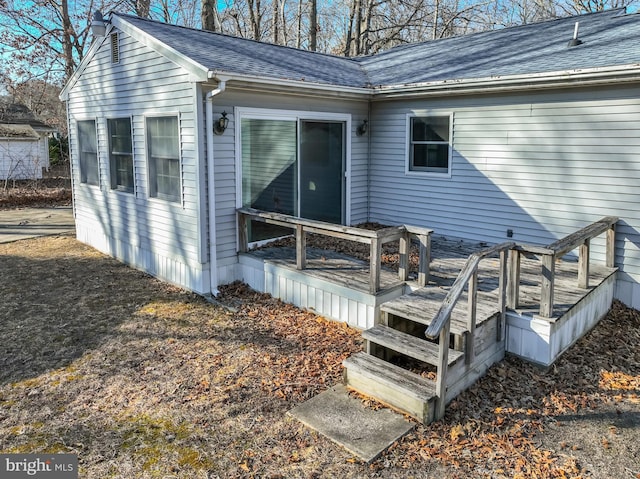 back of property featuring a shingled roof and a deck