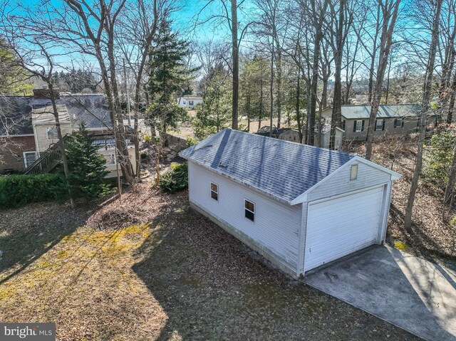 exterior space with a garage, roof with shingles, and an outdoor structure