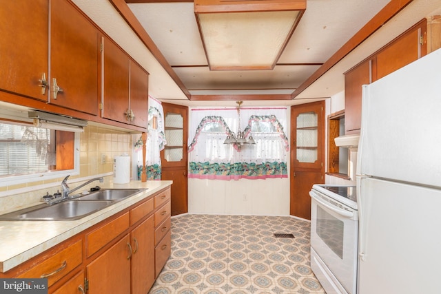 kitchen featuring white appliances, light countertops, a sink, and light floors