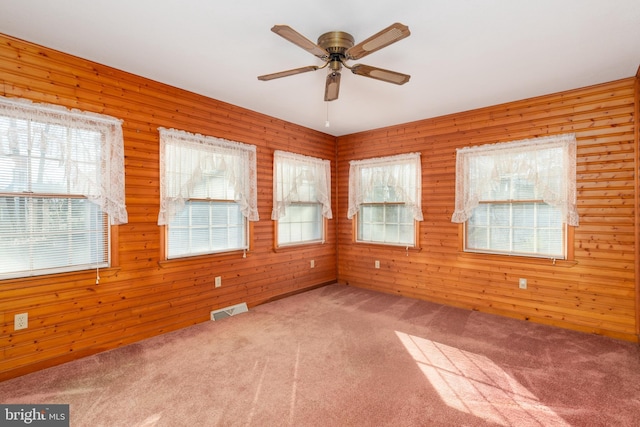 empty room with carpet floors, a healthy amount of sunlight, visible vents, and ceiling fan