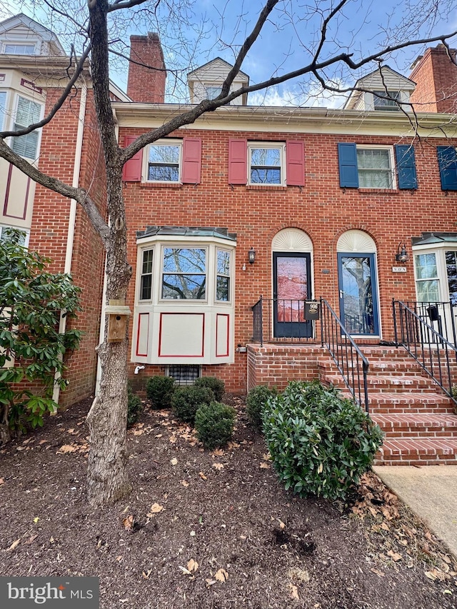 multi unit property featuring a chimney and brick siding