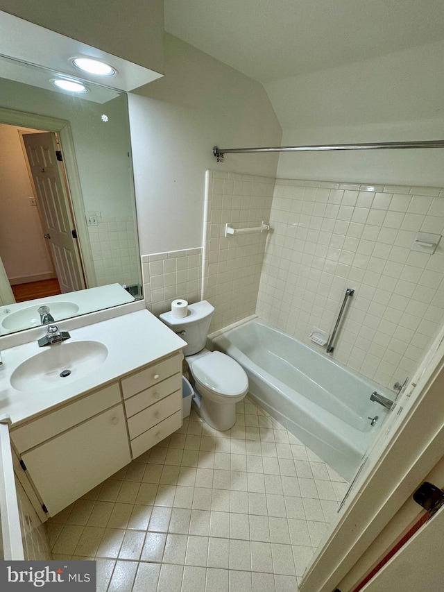 bathroom featuring shower / bathtub combination, toilet, vanity, tile walls, and tile patterned floors