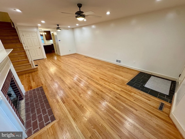 unfurnished living room featuring recessed lighting, visible vents, baseboards, stairs, and light wood-type flooring