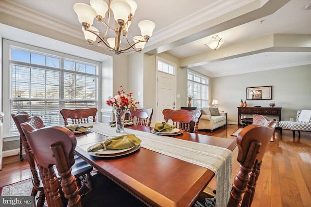 dining room featuring a notable chandelier, ornamental molding, and wood finished floors