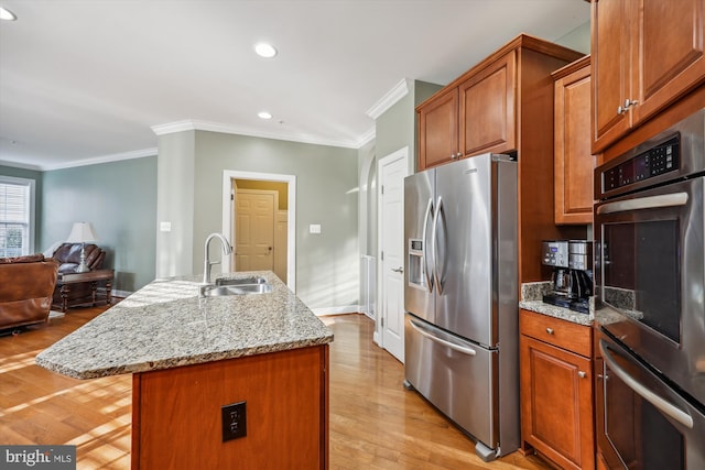 kitchen featuring brown cabinets, a kitchen island with sink, stainless steel appliances, and a sink