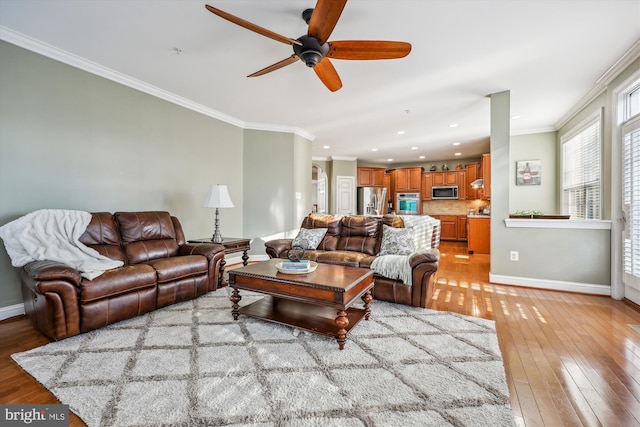 living area featuring recessed lighting, a ceiling fan, baseboards, light wood-type flooring, and crown molding