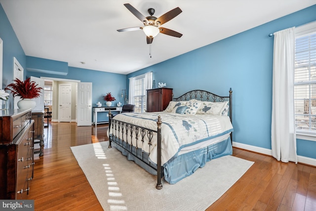 bedroom with a ceiling fan, wood-type flooring, and baseboards