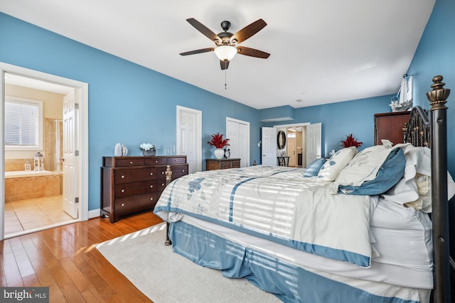 bedroom featuring multiple closets, ceiling fan, connected bathroom, and hardwood / wood-style floors