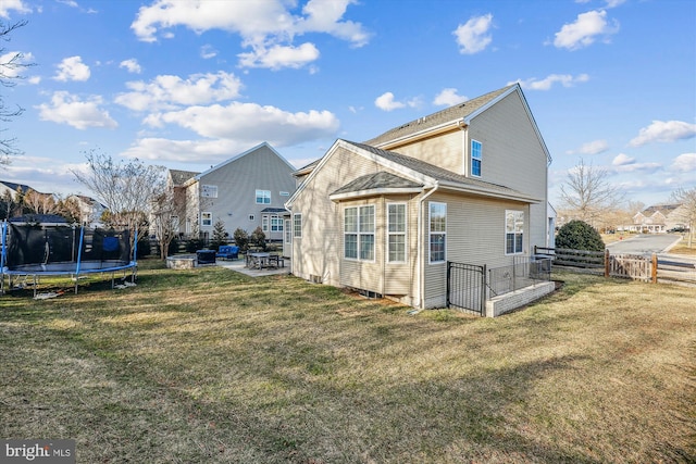 back of property with a yard, a trampoline, a patio area, and a fenced backyard