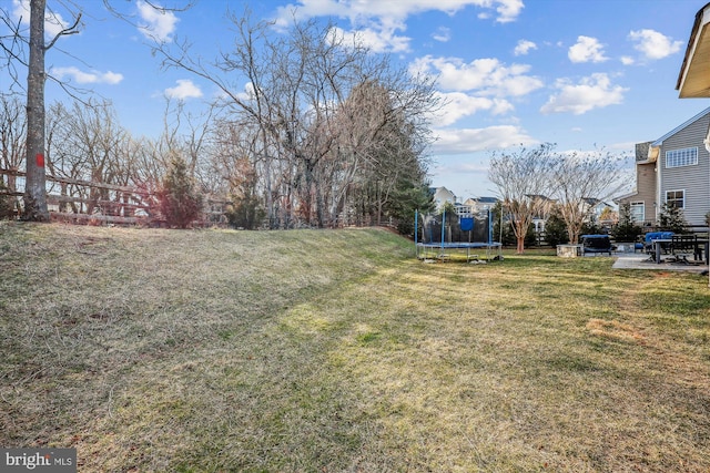 view of yard with a trampoline and a patio area