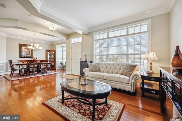 living room featuring crown molding, beamed ceiling, an inviting chandelier, and hardwood / wood-style flooring