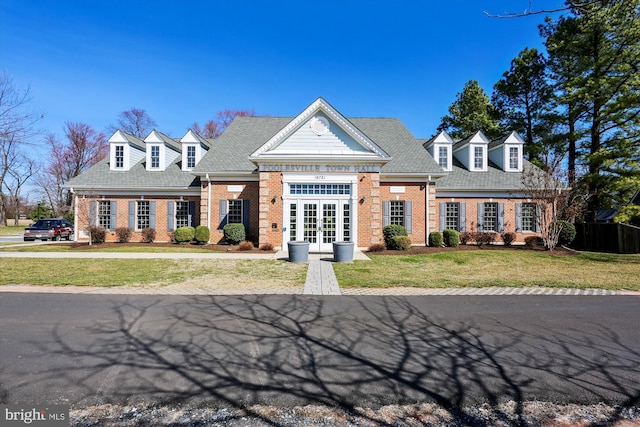 view of front of home featuring french doors, a front lawn, a shingled roof, and brick siding