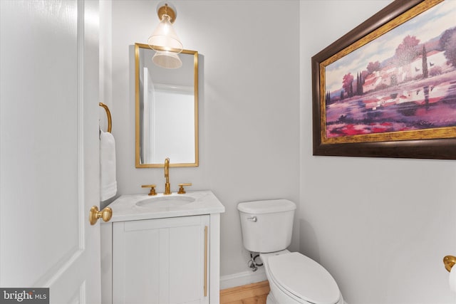 bathroom featuring baseboards, vanity, and toilet