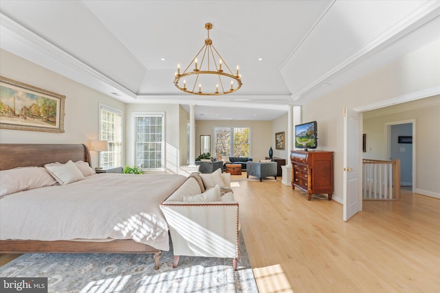 bedroom with baseboards, a raised ceiling, crown molding, light wood-style floors, and a notable chandelier