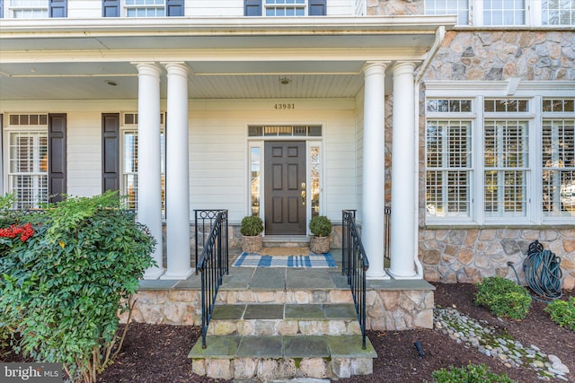 doorway to property with stone siding and covered porch