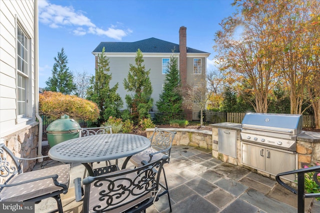 view of patio with outdoor dining space, fence, and area for grilling