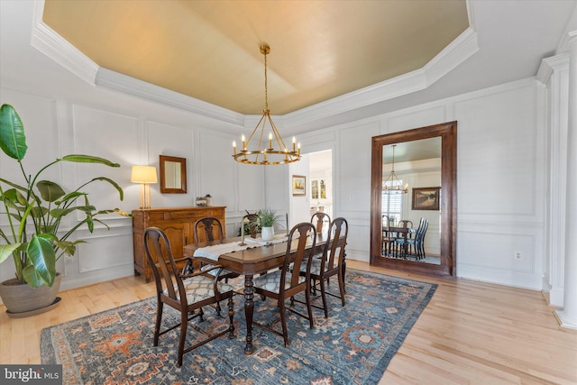 dining room with a chandelier, a raised ceiling, and a decorative wall