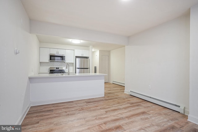 kitchen with stainless steel appliances, a baseboard radiator, a peninsula, and light wood-style flooring