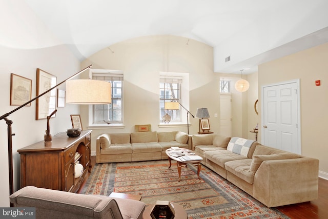 living area featuring lofted ceiling, visible vents, wood finished floors, and stairs