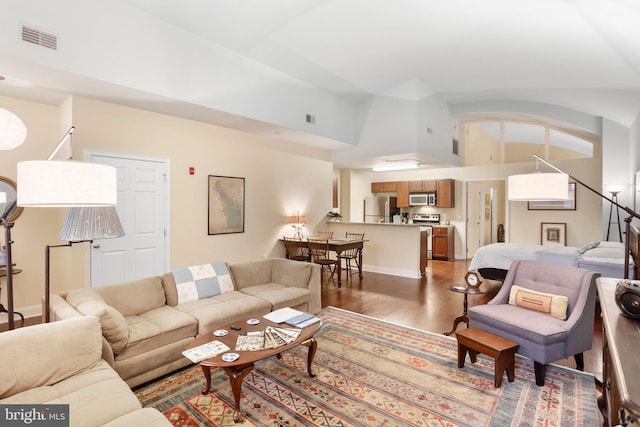 living room with high vaulted ceiling, baseboards, visible vents, and wood finished floors