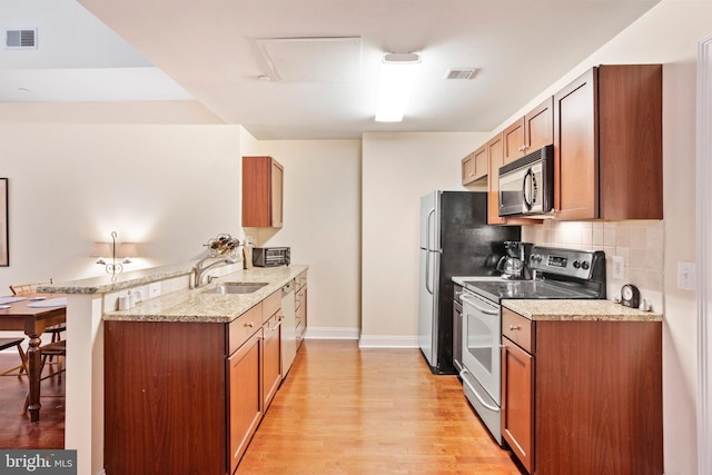 kitchen featuring brown cabinets, stainless steel electric stove, light stone countertops, black microwave, and a peninsula