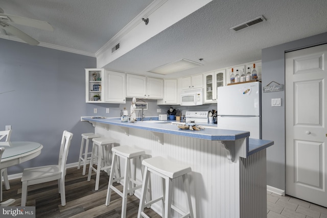 kitchen featuring a breakfast bar, open shelves, glass insert cabinets, white cabinetry, and white appliances