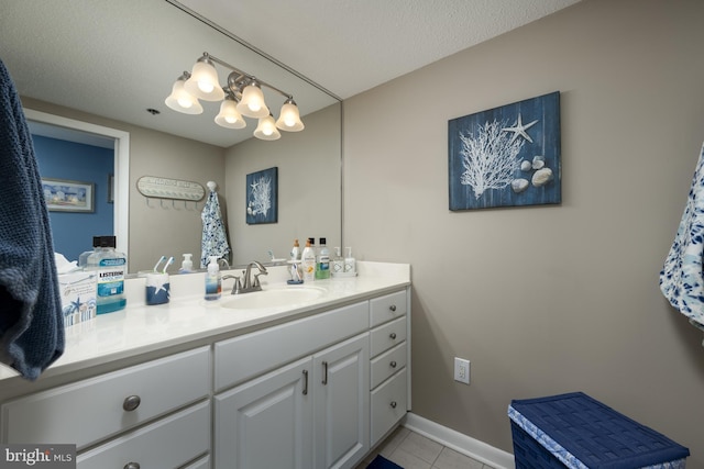 bathroom with a textured ceiling, tile patterned flooring, vanity, and baseboards