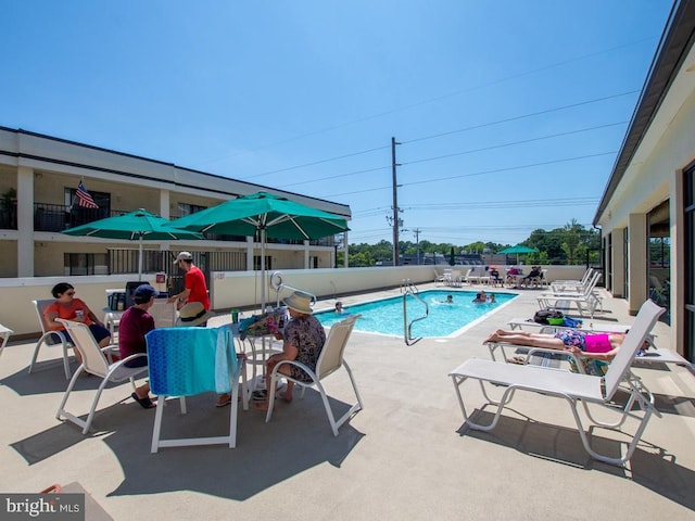 community pool with a patio area and fence