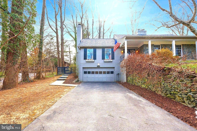 view of front of property featuring an attached garage, stone siding, driveway, and a chimney