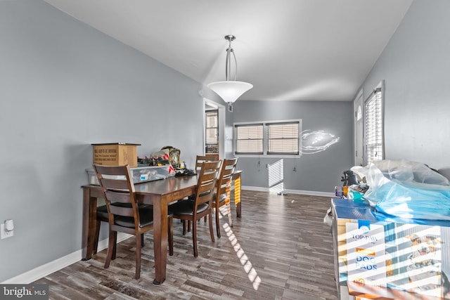 dining space featuring vaulted ceiling, baseboards, and wood finished floors