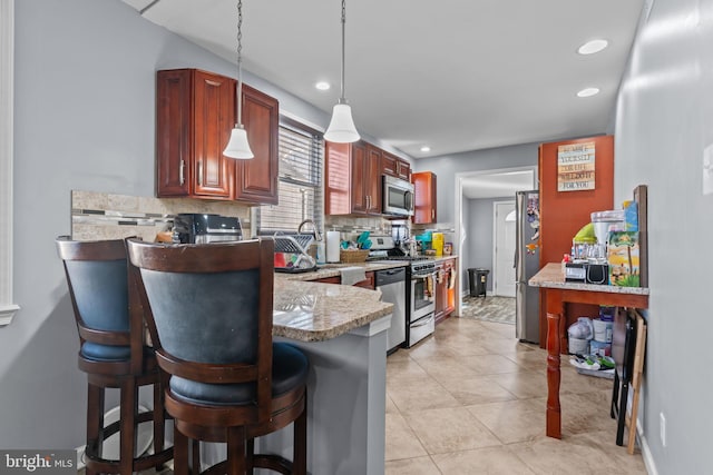 kitchen with decorative light fixtures, stainless steel appliances, decorative backsplash, a peninsula, and a kitchen bar