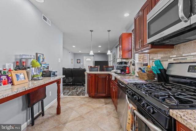 kitchen featuring stainless steel appliances, visible vents, hanging light fixtures, backsplash, and a sink