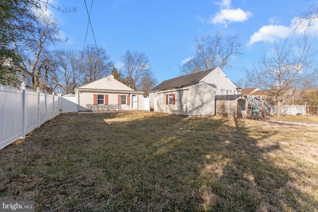 back of property featuring a fenced backyard, stairs, a lawn, and an outdoor structure