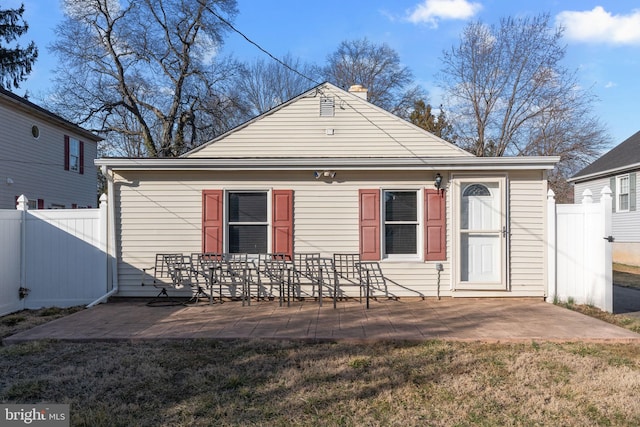 back of property with a yard, a patio area, fence, and a chimney