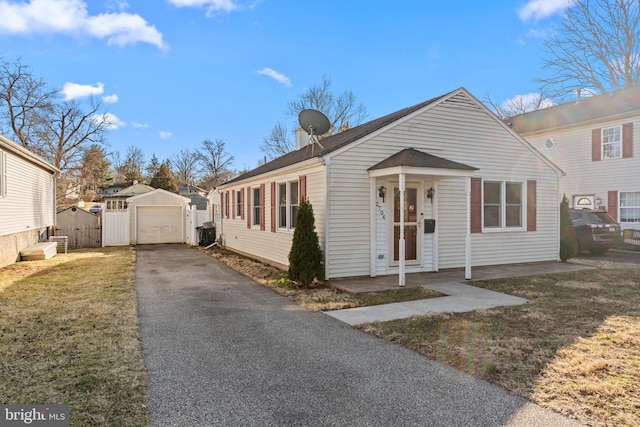 bungalow with an outbuilding, fence, a garage, driveway, and a front lawn